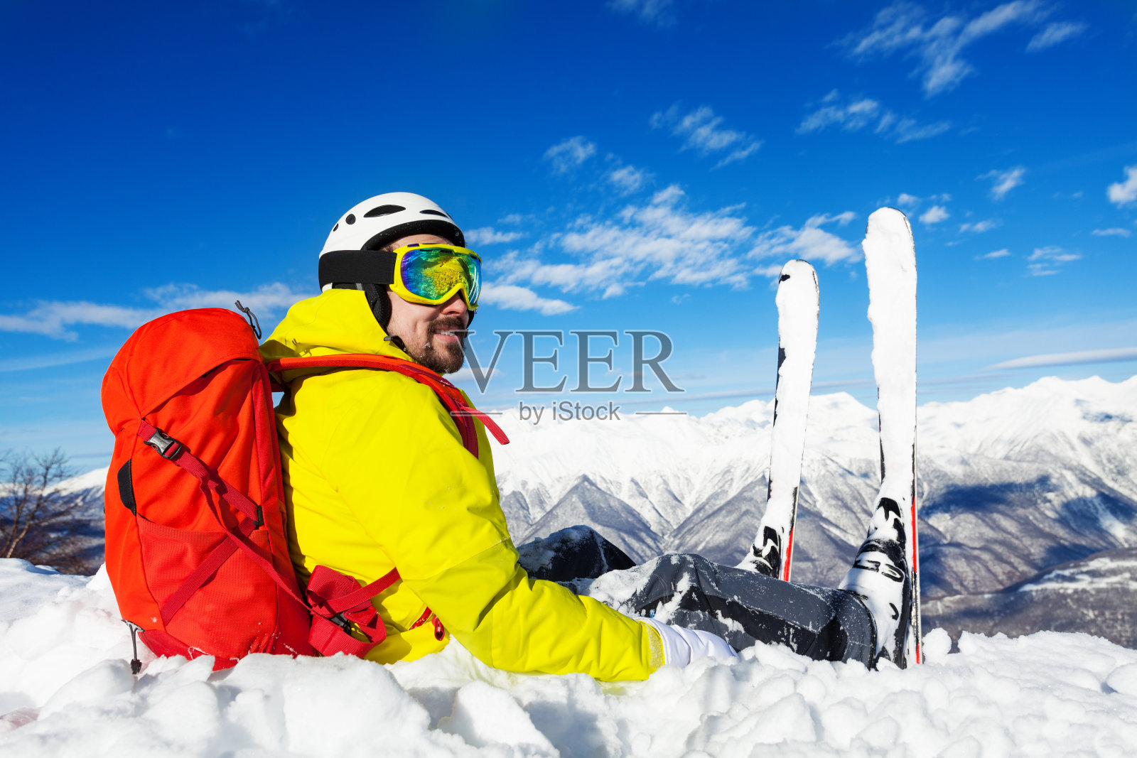 一个背着背包的滑雪者坐在山顶上照片摄影图片
