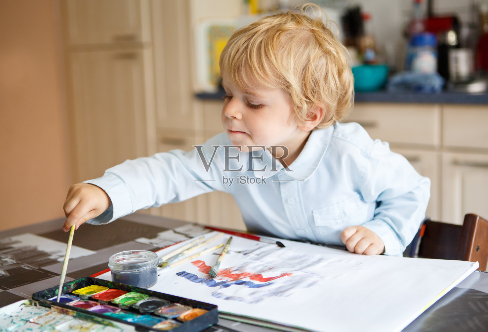 两岁的可爱男孩用颜料画画。照片摄影图片