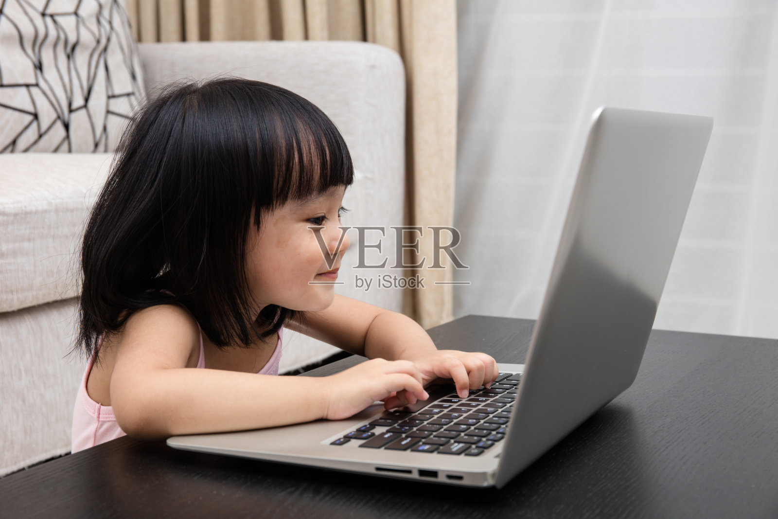微笑的亚洲中国小女孩在家里使用笔记本电脑照片摄影图片