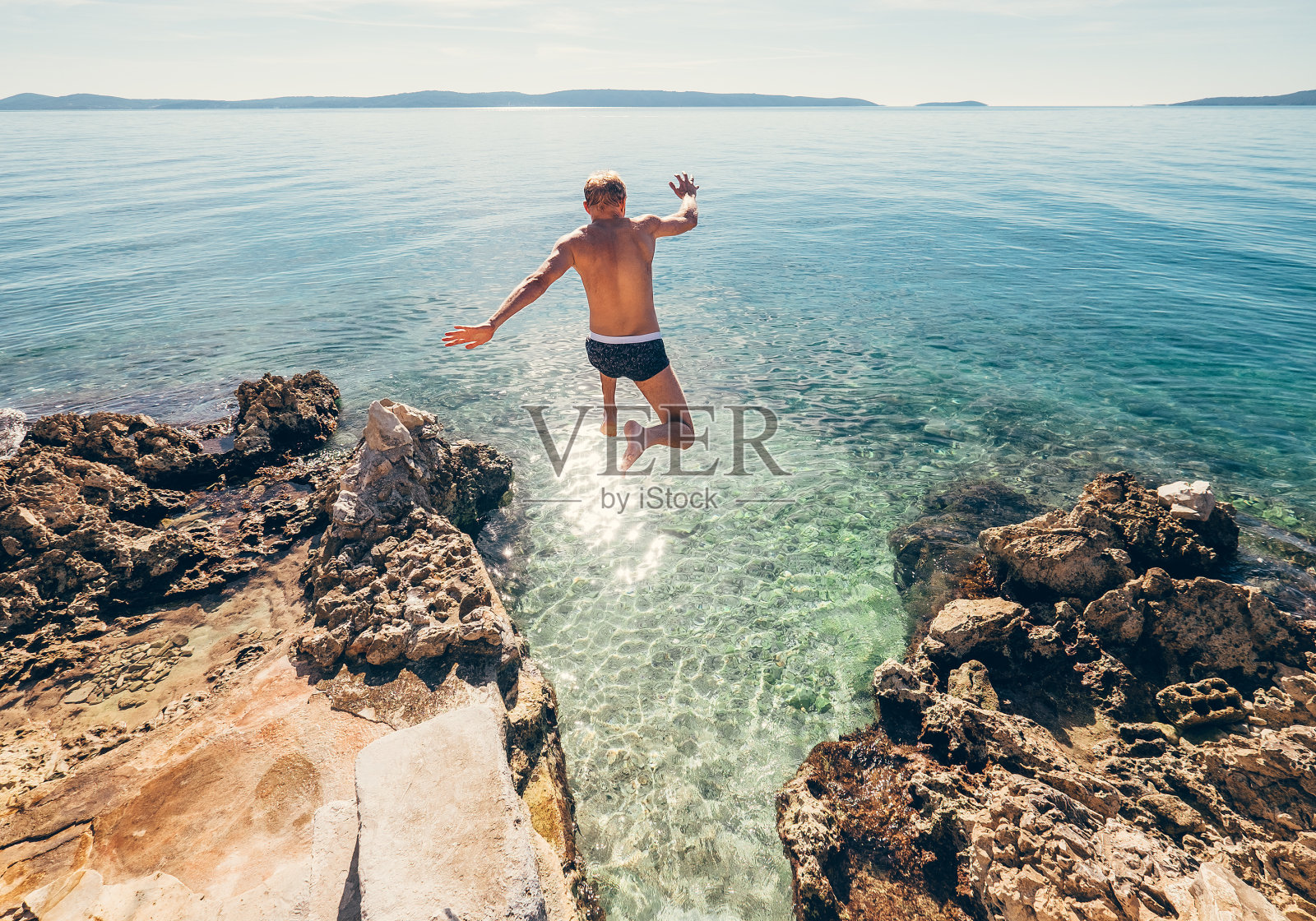 男人跳进蓝色的海水里照片摄影图片