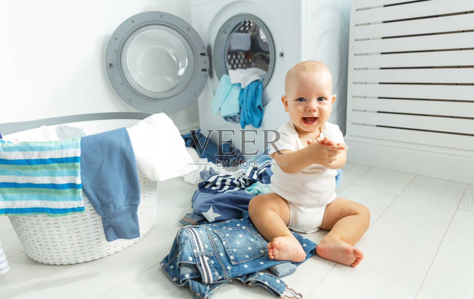 开心的宝贝男孩洗衣服，笑在洗衣房照片摄影图片