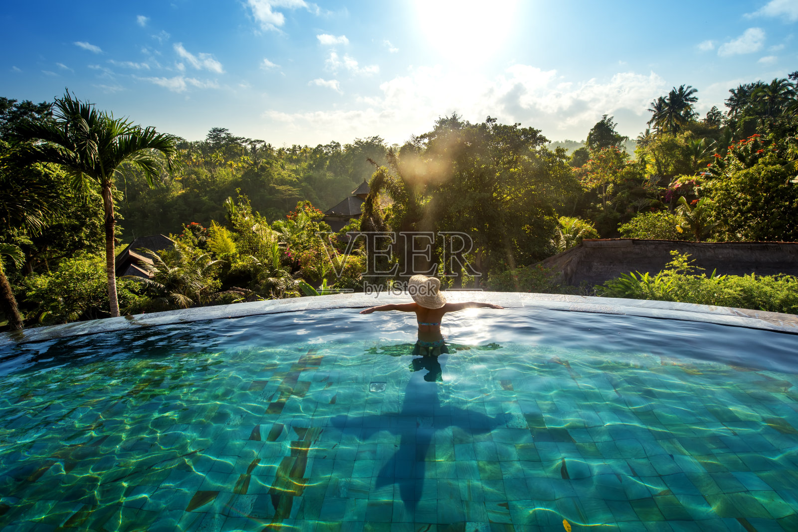 幸福的概念。在豪华度假村的游泳池里享受日光浴的女人照片摄影图片