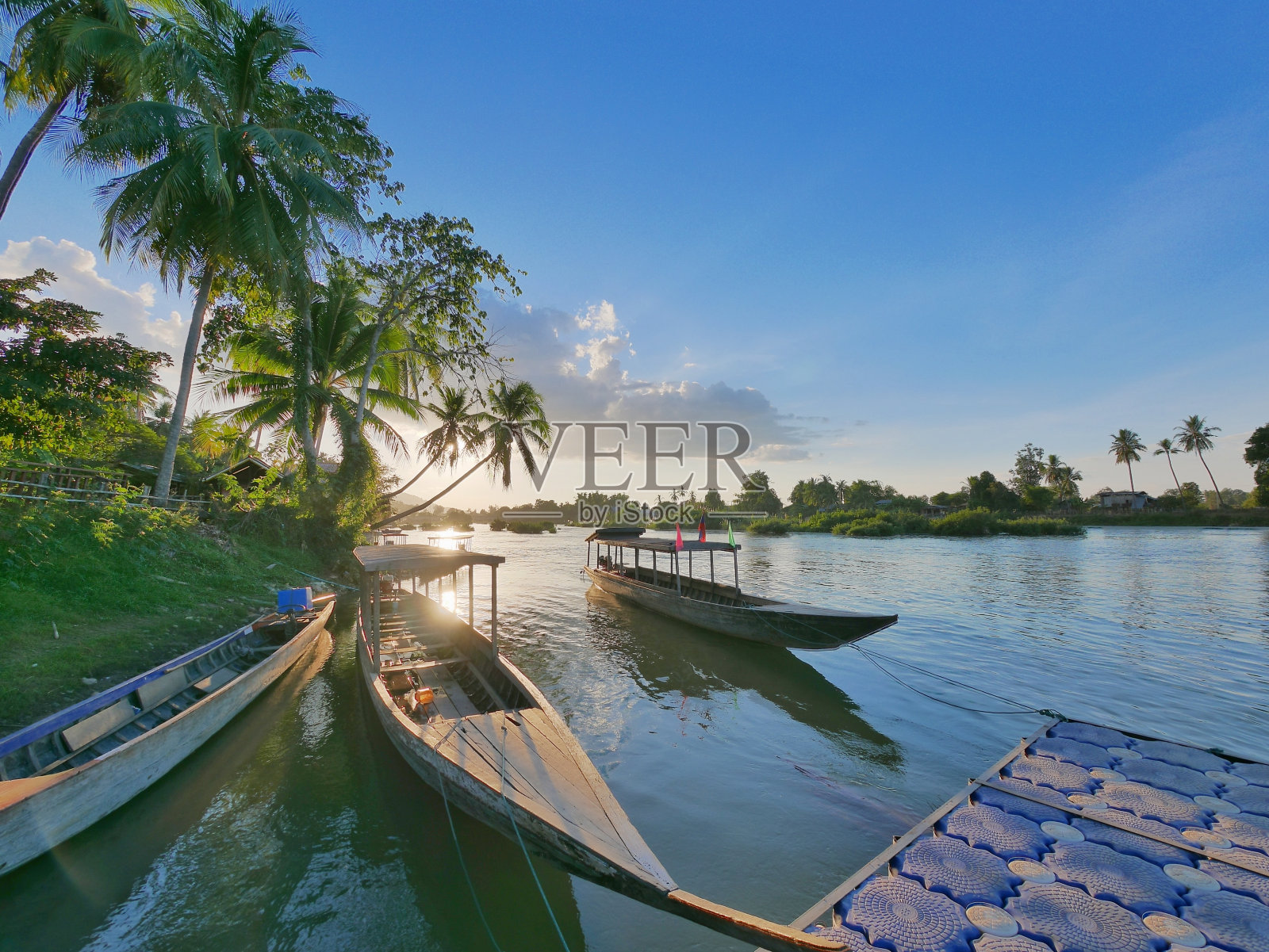 日落时分，平静的湄公河上的长尾船照片摄影图片