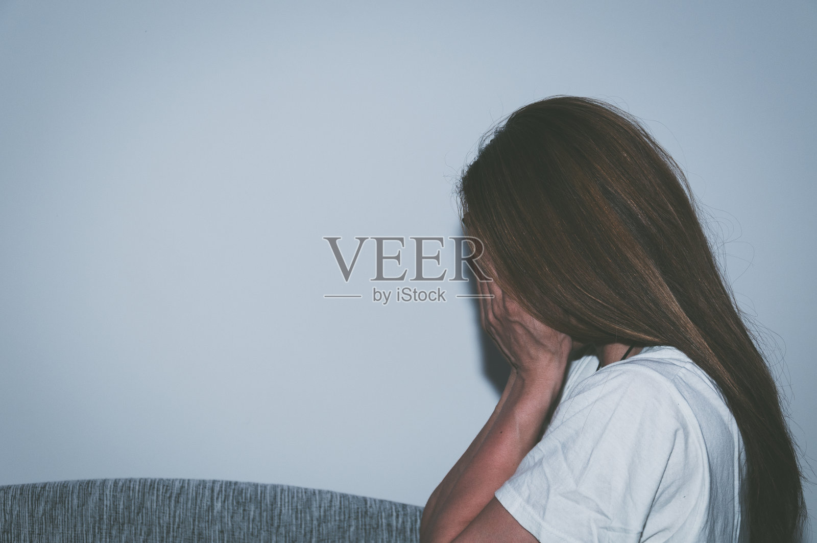 可怜的年轻女子独自坐在自己房间的床上，沮丧地用手捂着脸哭泣。照片摄影图片