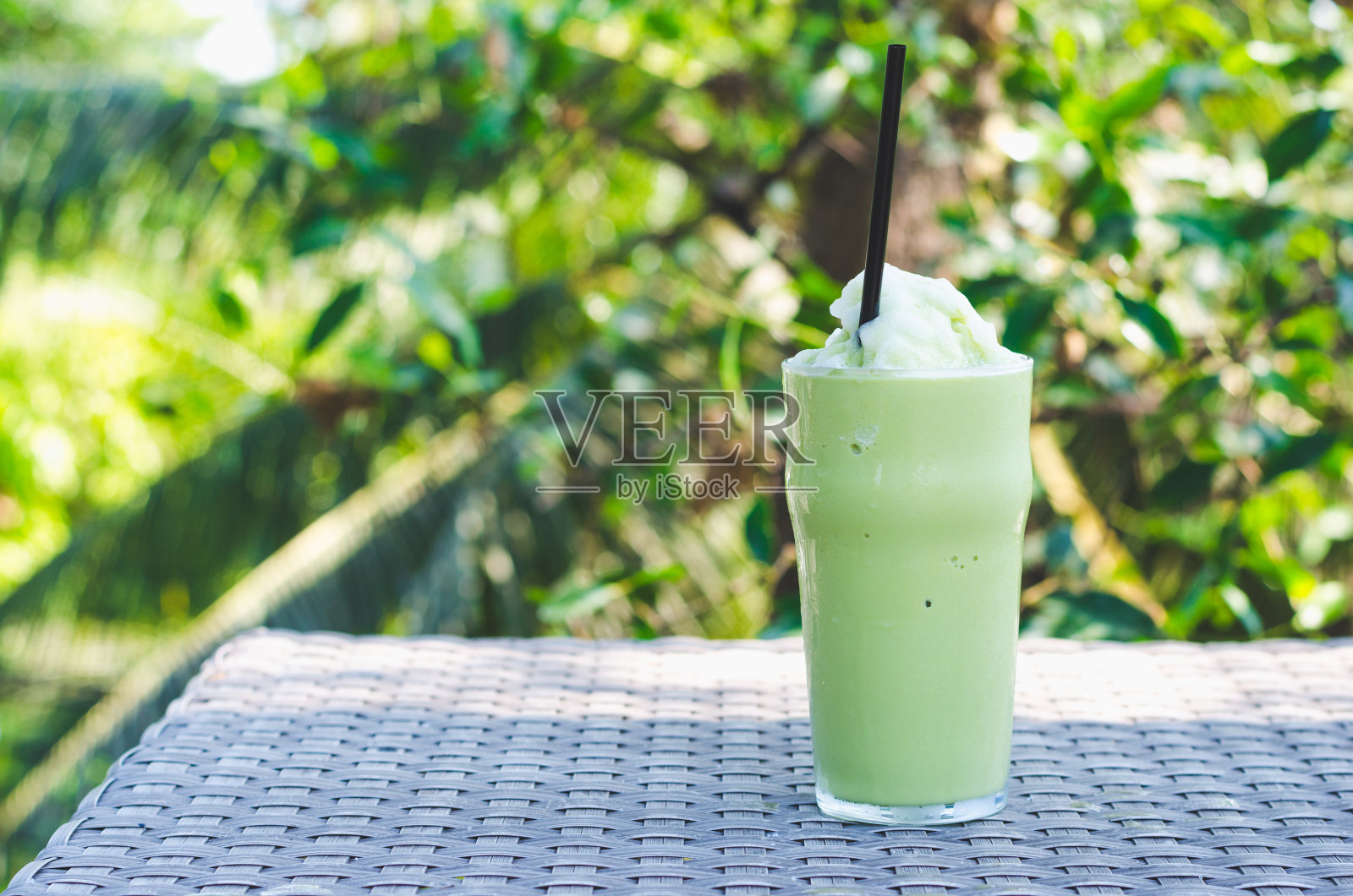 一杯绿茶冰沙，以绿色植物为背景的冰摇。照片摄影图片