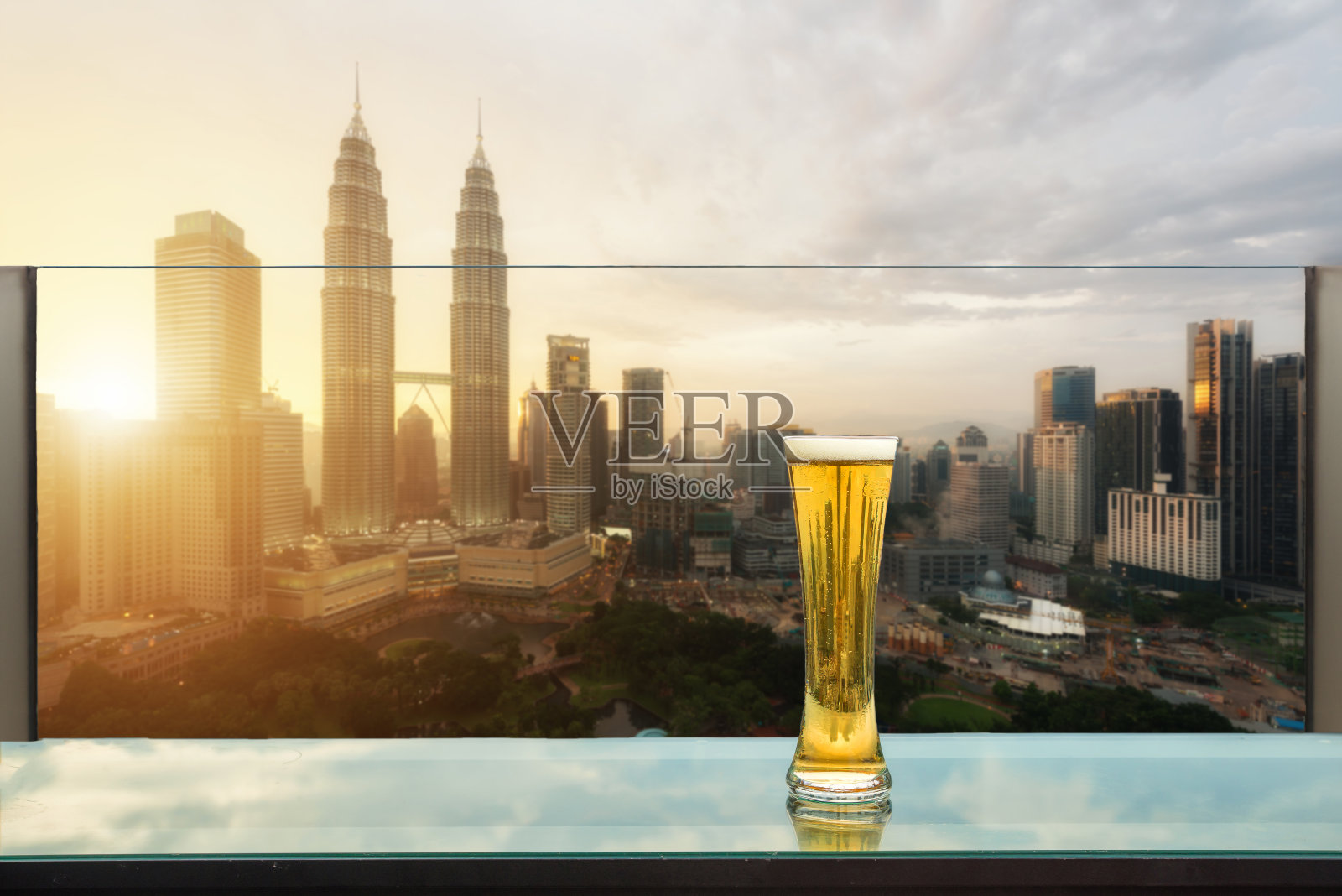 马来西亚吉隆坡，屋顶酒吧的桌上放着啤酒和泡沫啤酒，背景是吉隆坡摩天大楼。照片摄影图片