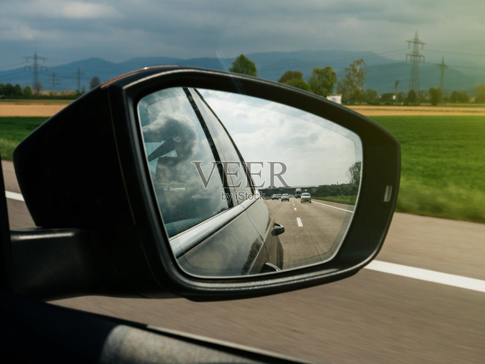 在德国一辆汽车的后视镜中看到的山脉、汽车和高速公路照片摄影图片