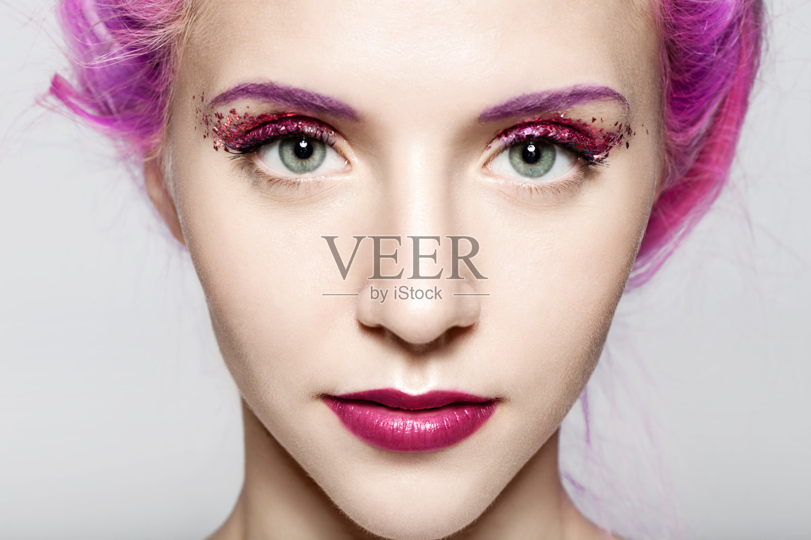 一个女人的脸的特写与时尚的紫色调闪闪发光的化妆照片摄影图片