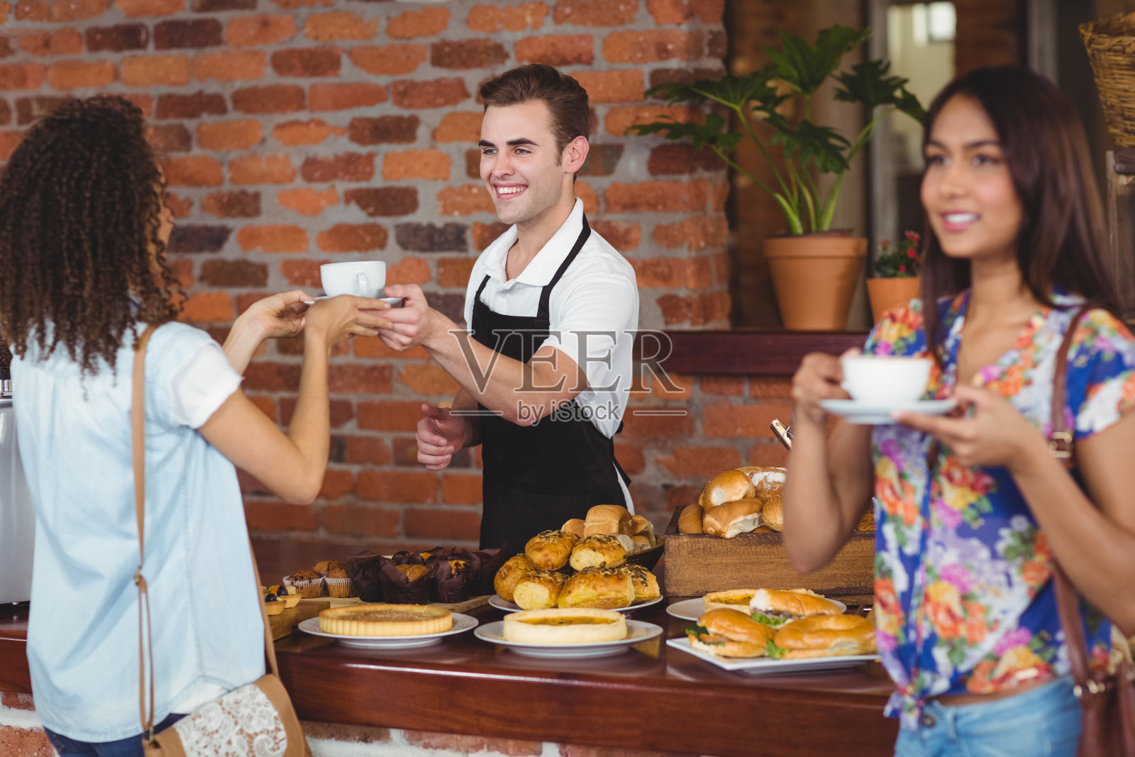 微笑的咖啡师给漂亮的顾客咖啡照片摄影图片