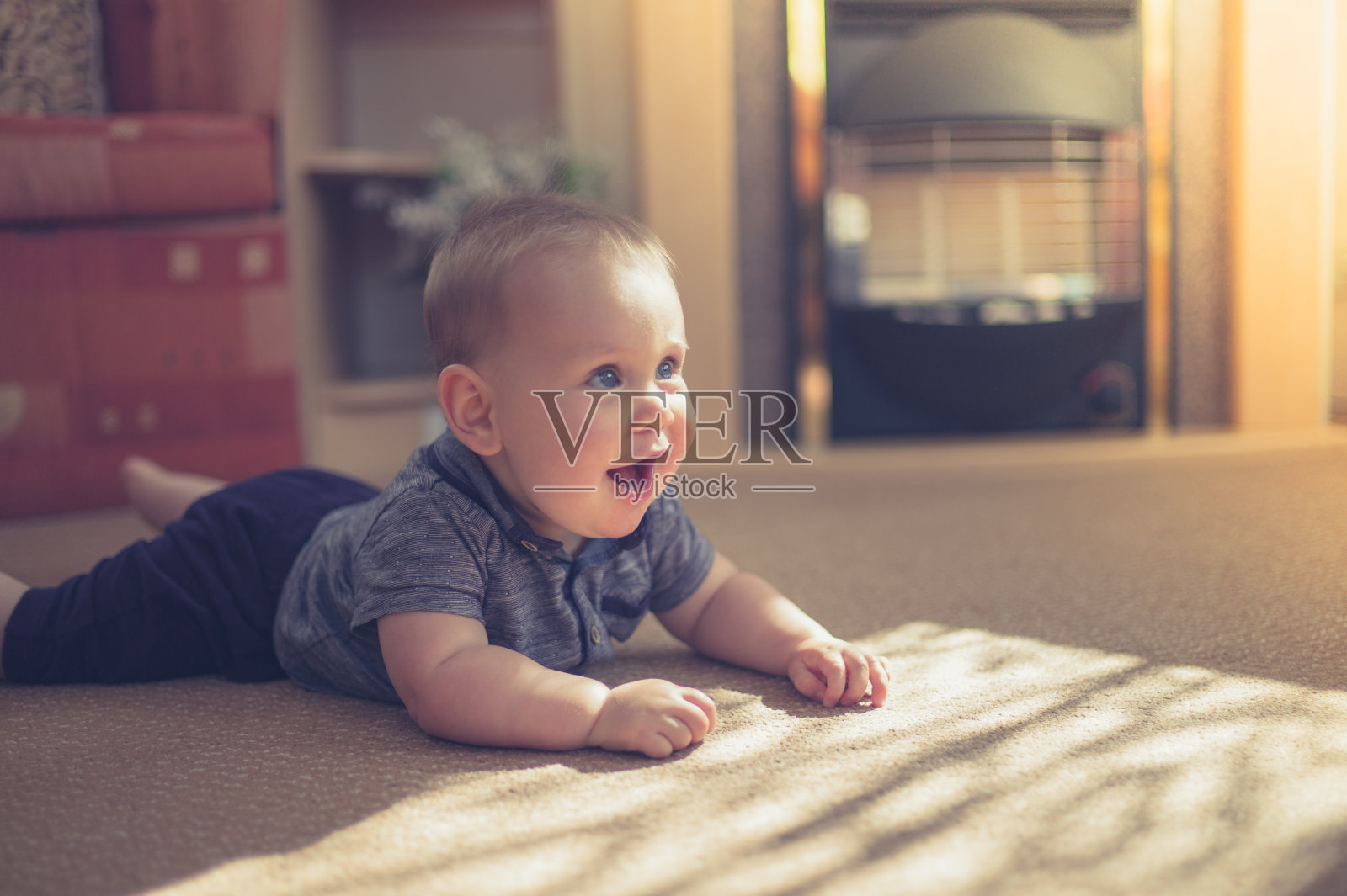 阳光下，可爱的婴儿在地毯上爬行照片摄影图片