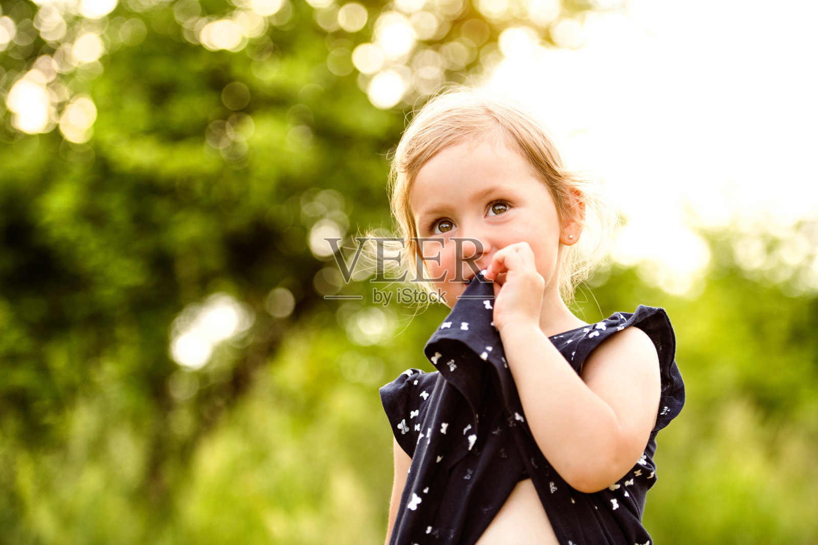 可爱的小女孩在绿色阳光明媚的夏日大自然中。照片摄影图片