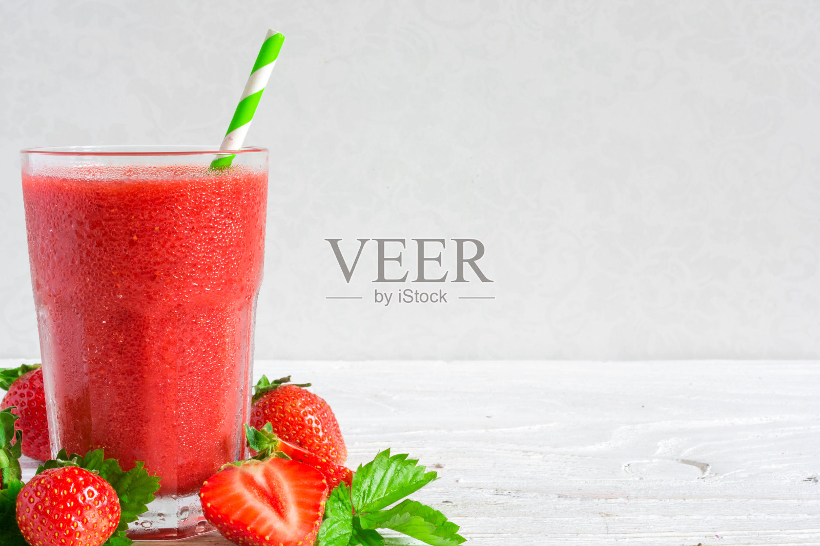 草莓冰沙在一个玻璃杯，吸管和新鲜浆果照片摄影图片