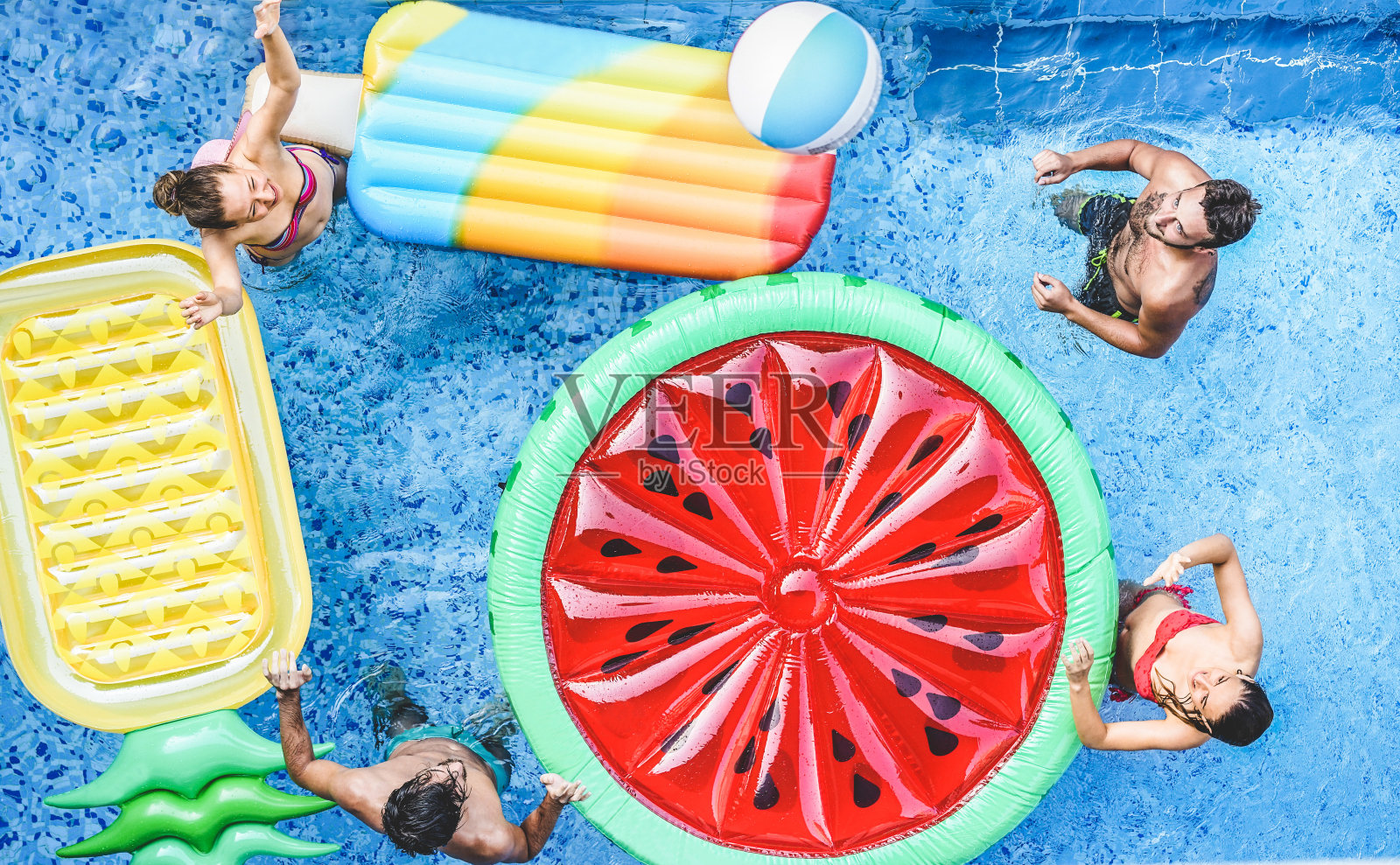 快乐的朋友在游泳池里玩球-年轻人在暑假度假-旅游，假期，青年，友谊和热带概念-季节性色彩色调过滤照片摄影图片