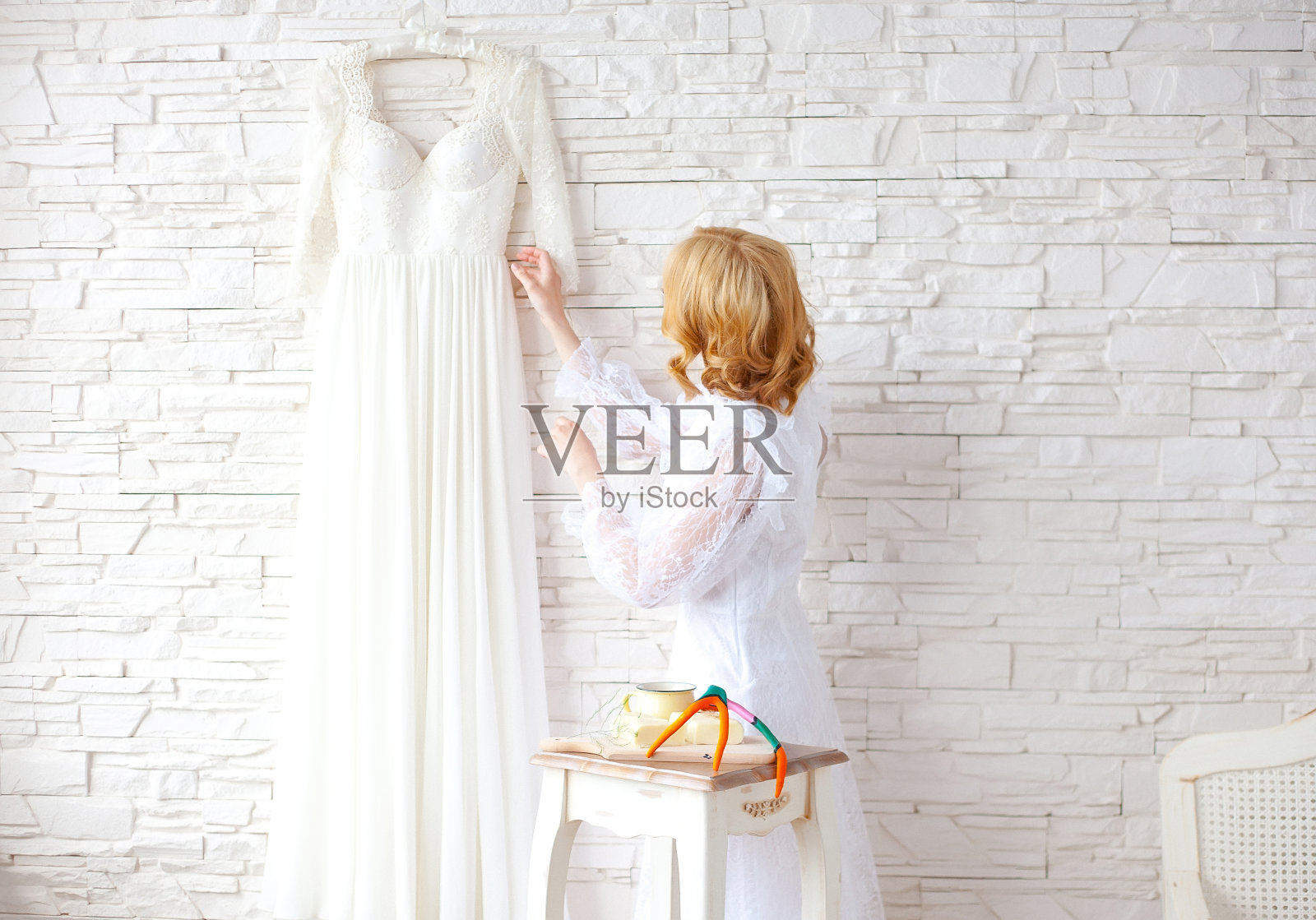 美丽的金发新娘靠近白色砖墙照片摄影图片