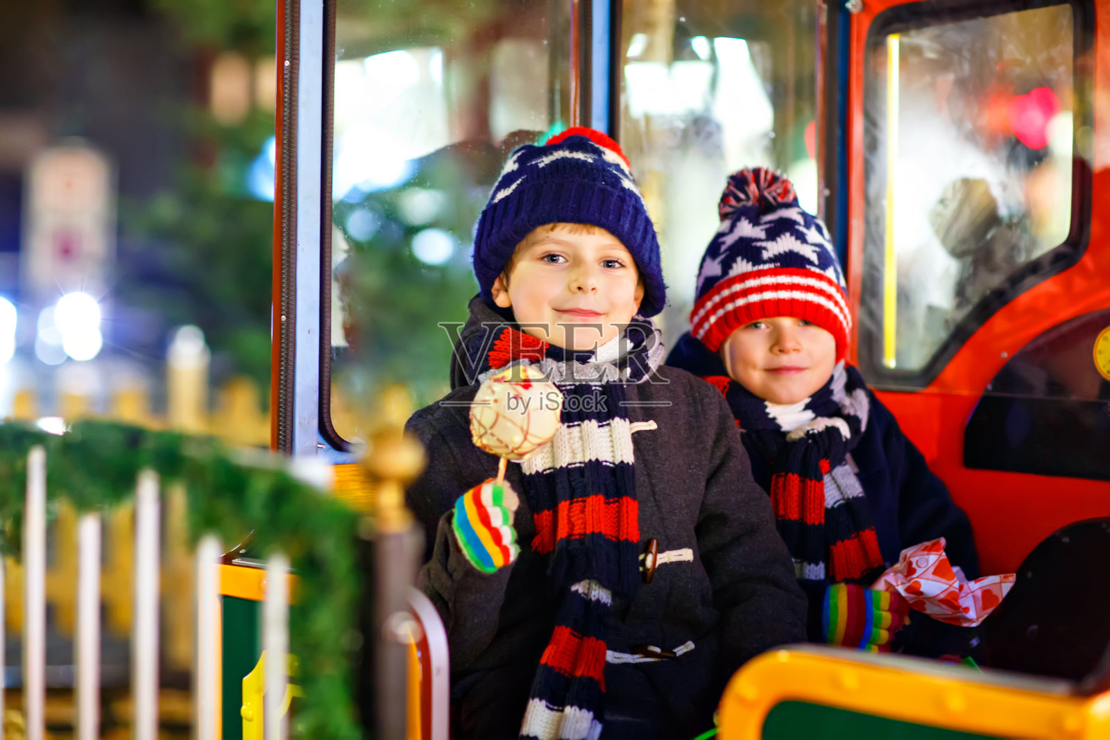两个小男孩在圣诞市场的旋转木马上照片摄影图片