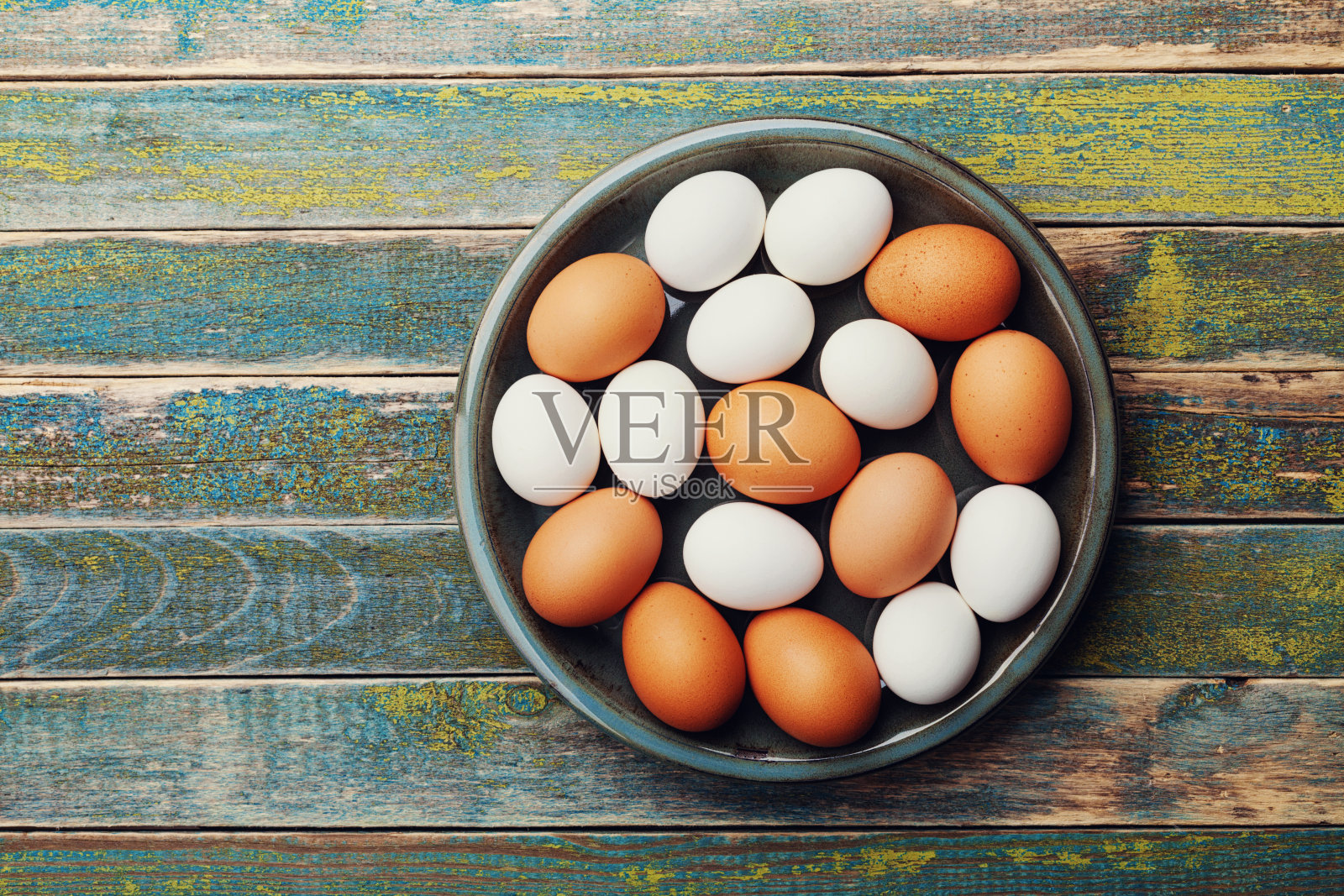 质朴的桌子上，白色和棕色的鸡蛋放在复古碗里。有机食品和农业食品。平的。照片摄影图片
