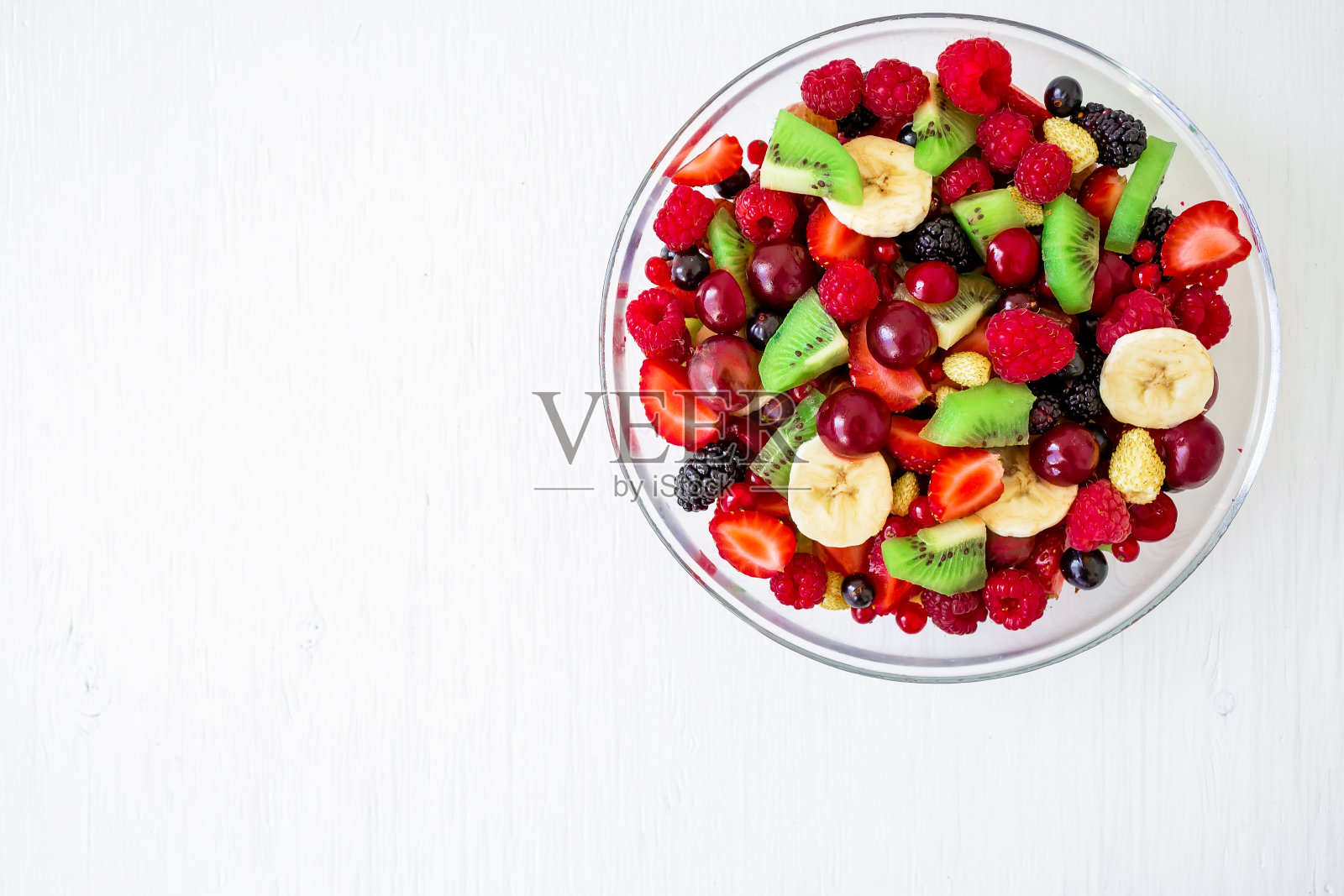 美味新鲜的水果沙拉在白色的木制背景。前视图。天然食品照片摄影图片