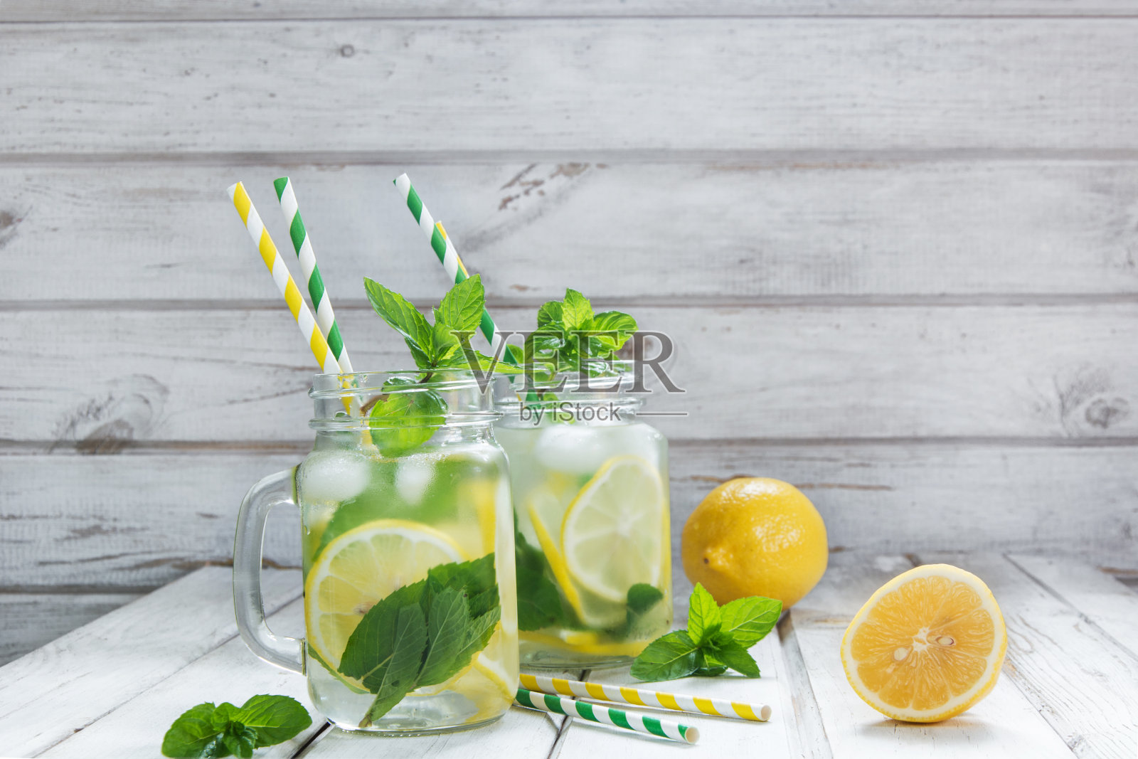 夏季饮料，水排毒柠檬，冰和薄荷在梅森瓶在白色木制背景。照片摄影图片