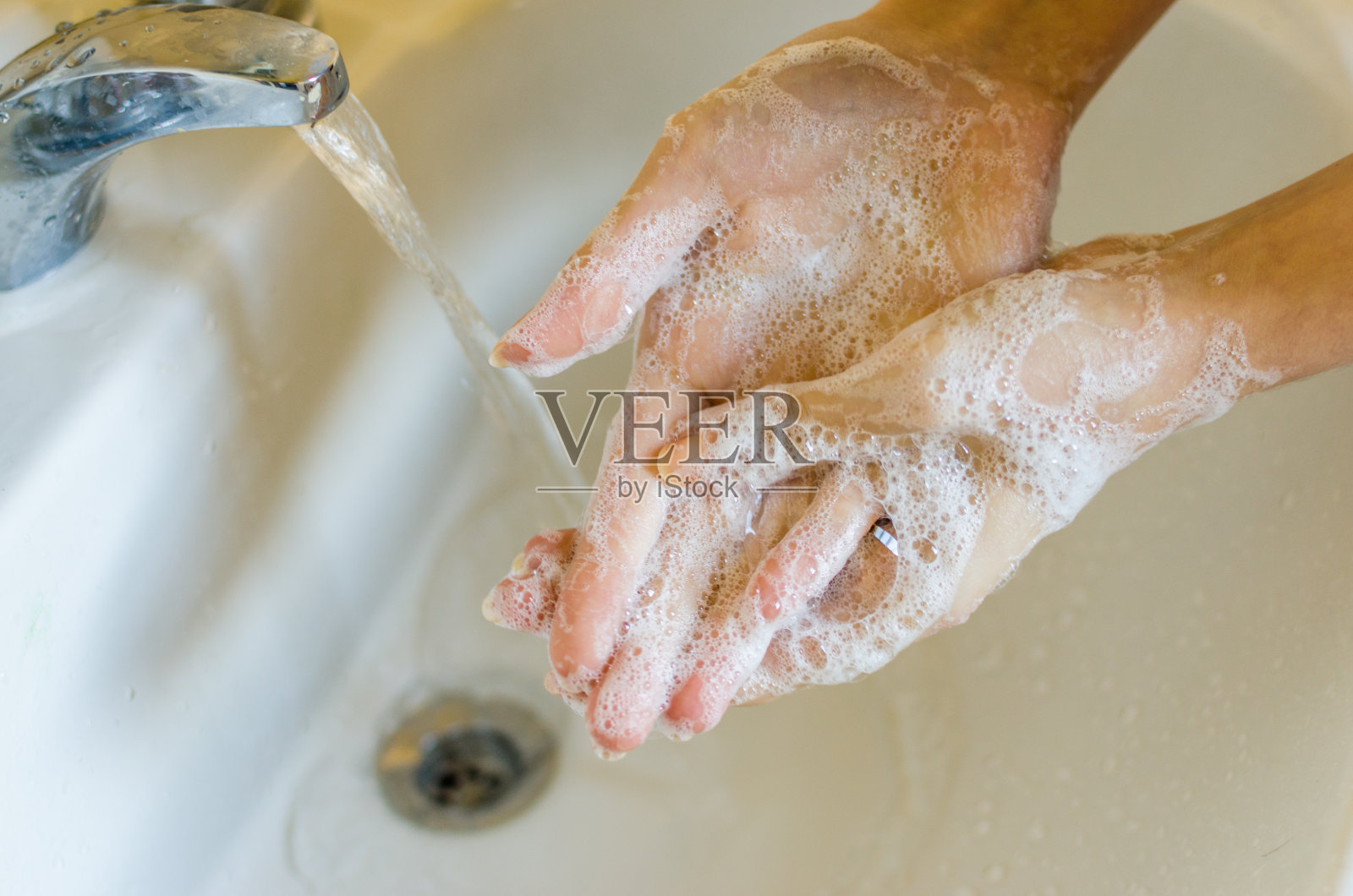 手指长指甲长的妇女在家用低过敏的肥皂洗手照片摄影图片