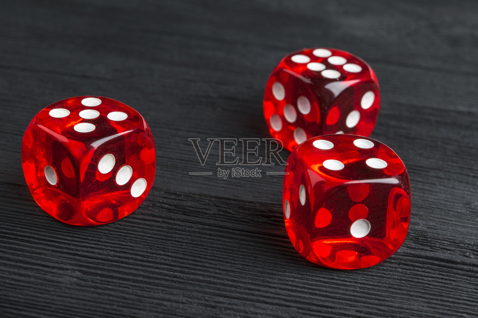 风险概念-玩骰子在黑色木制背景。用骰子玩游戏红色的赌场骰子。滚动骰子的概念商业风险，机会，好运或赌博照片摄影图片