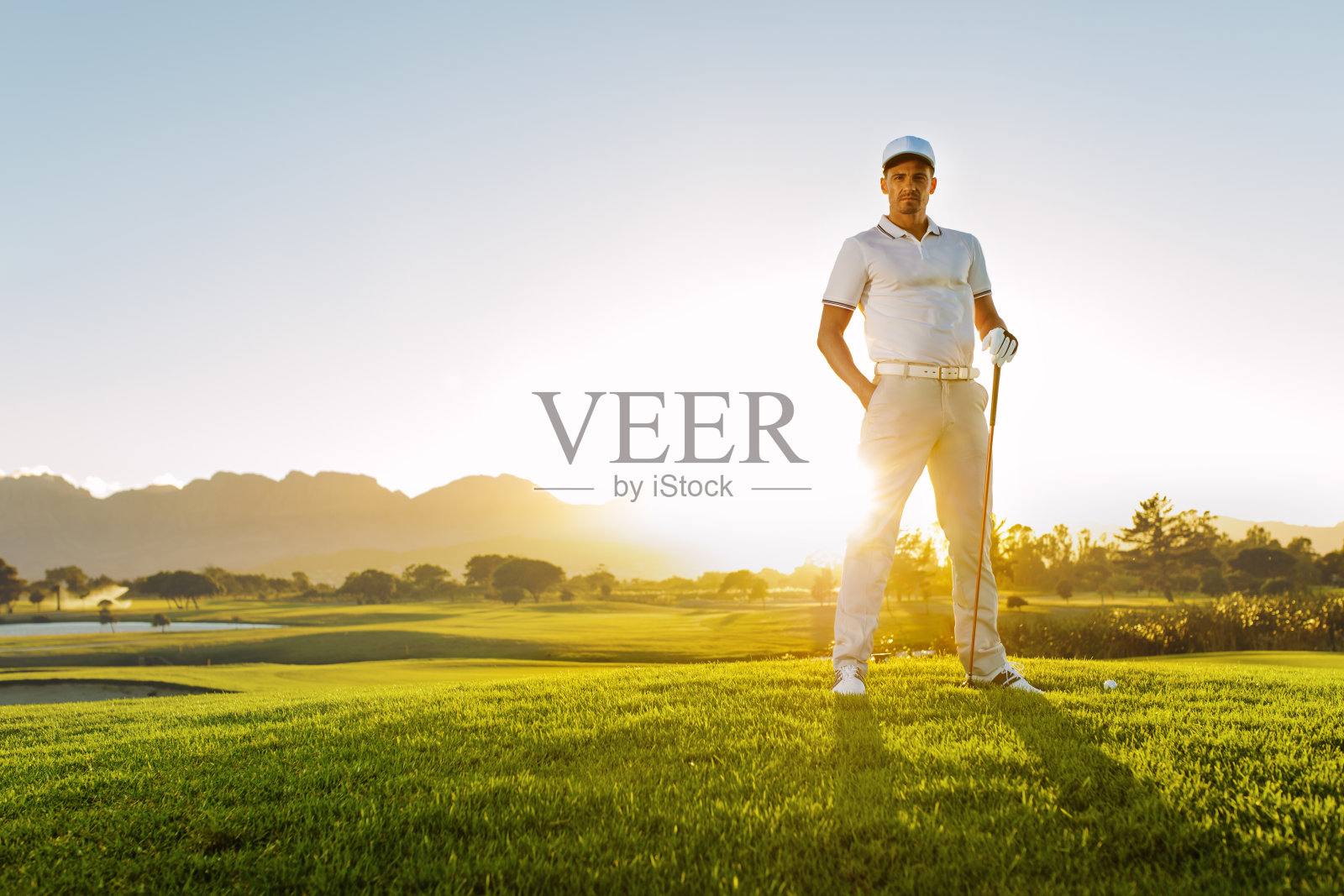 夏日里，年轻的男性高尔夫球手站在高尔夫球场上照片摄影图片