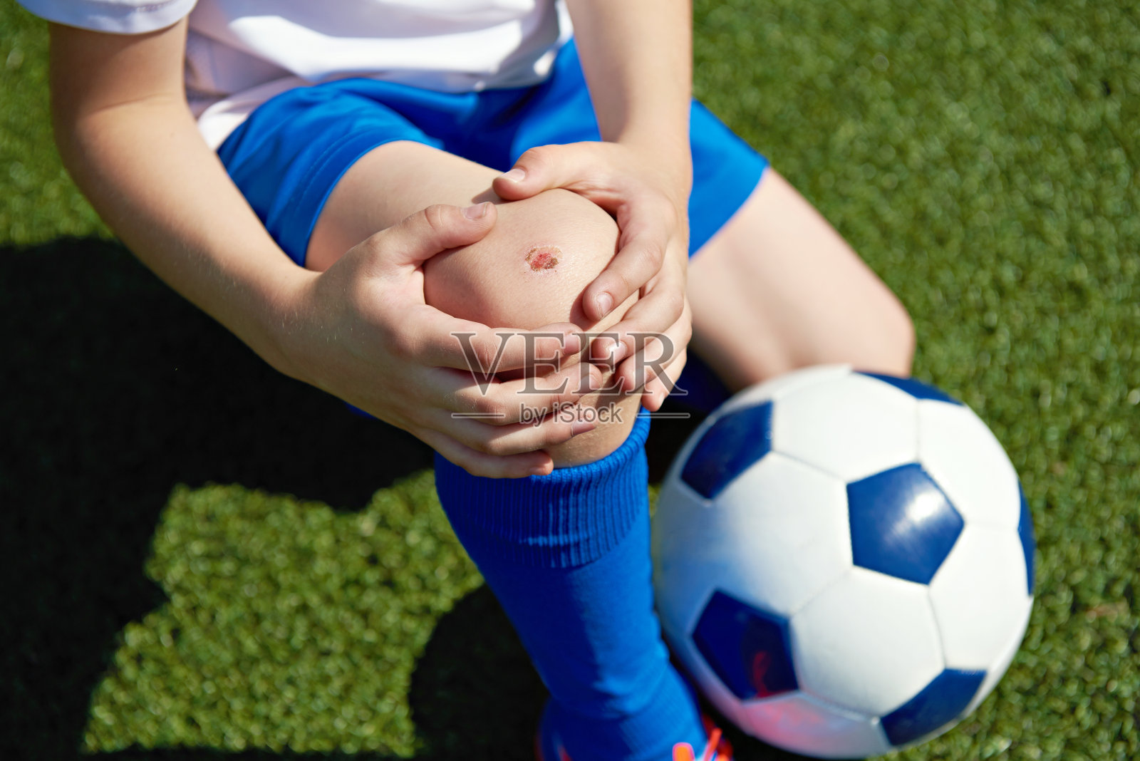 男孩踢足球时膝盖受伤照片摄影图片
