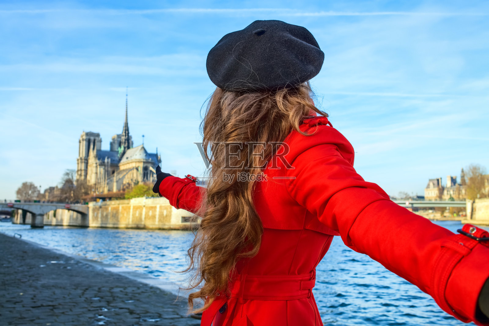一个女人牵着朋友的手，指着巴黎圣母院照片摄影图片