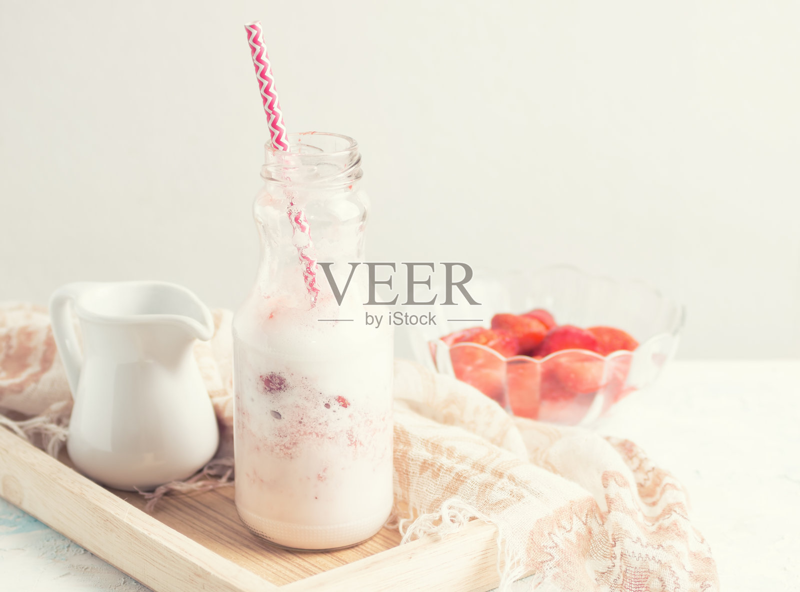 玻璃瓶装草莓奶昔，配料放在白色桌子上照片摄影图片