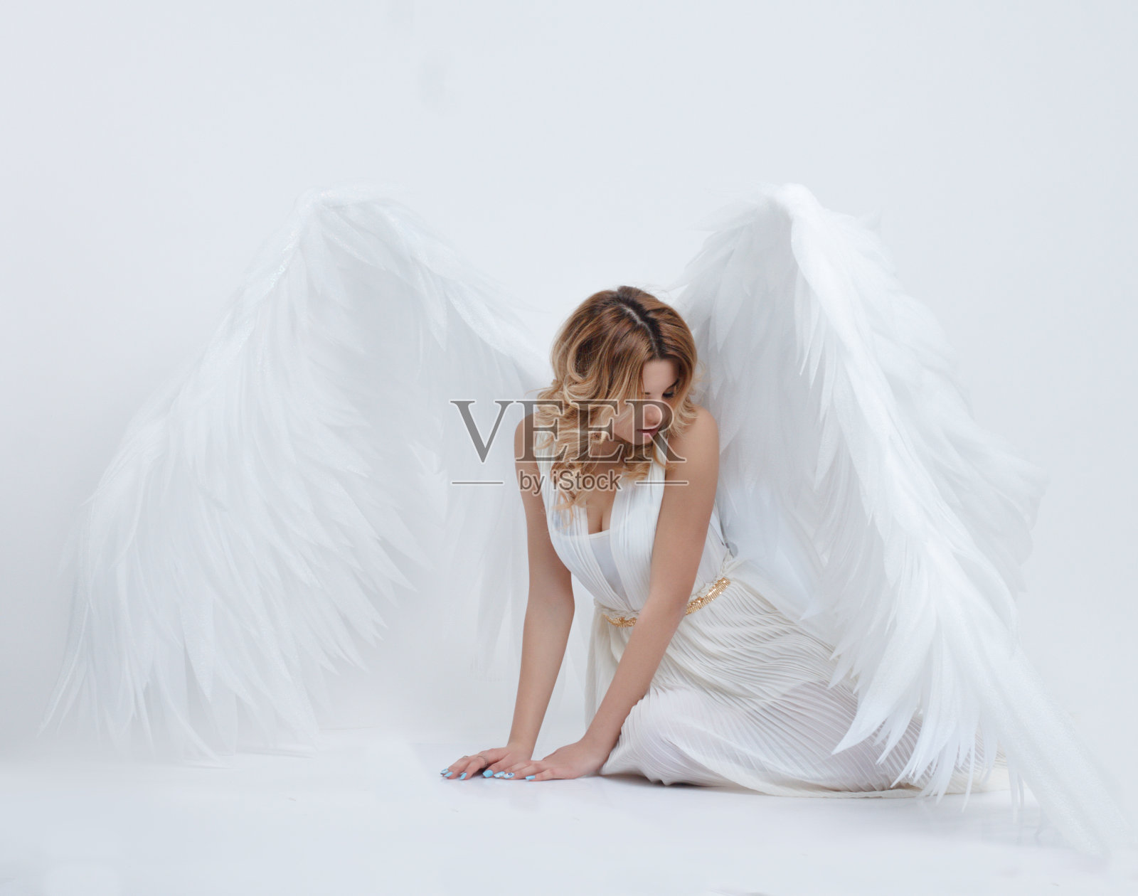 漂亮的年轻模特，长着大大的天使翅膀坐在工作室里照片摄影图片
