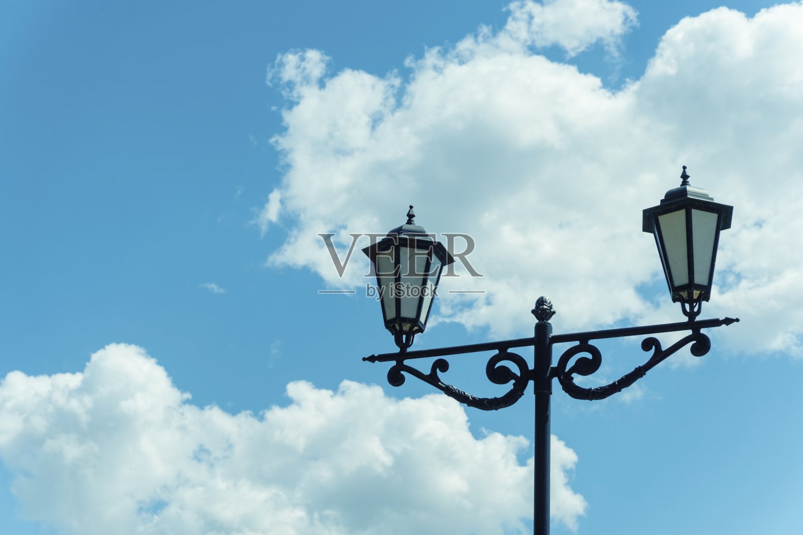 旧灯柱映衬着蓝天和白云。照片摄影图片
