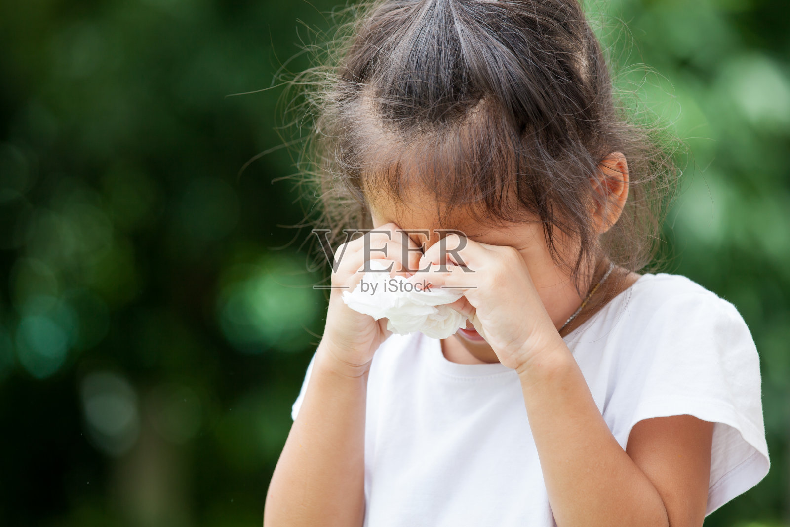 伤心的亚洲小女孩哭着，手里拿着纸巾照片摄影图片