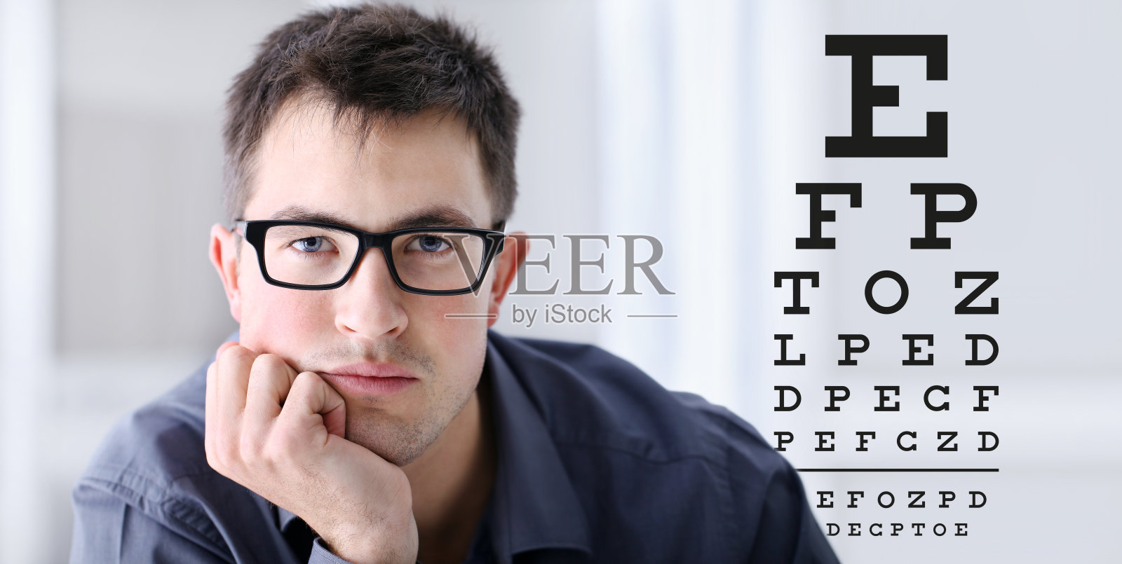 男面戴眼镜视力测试表背景，眼科检查眼科概念照片摄影图片