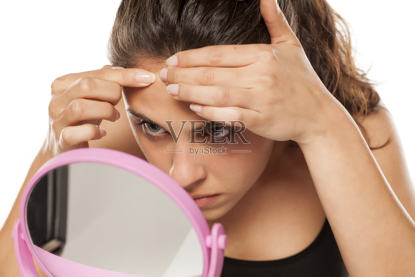 年轻女子在镜子前捏着脸上的青春痘照片摄影图片