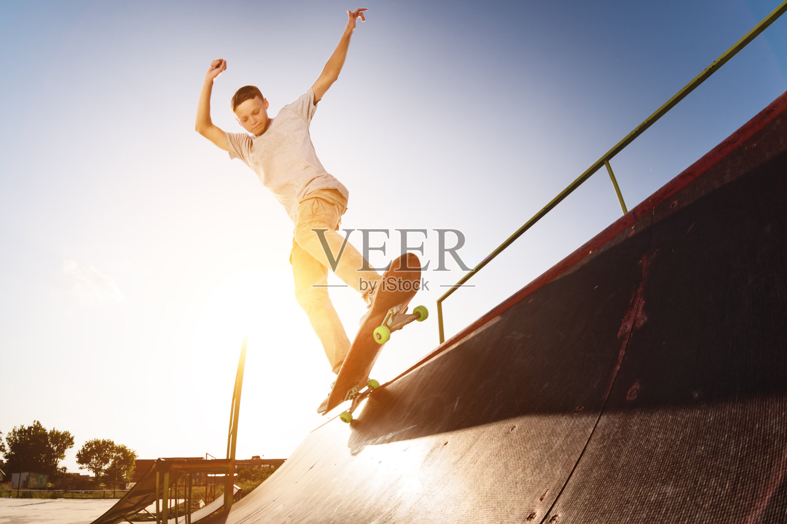 在一个滑板公园里，一个十几岁的滑板手挂在滑板的斜坡上照片摄影图片