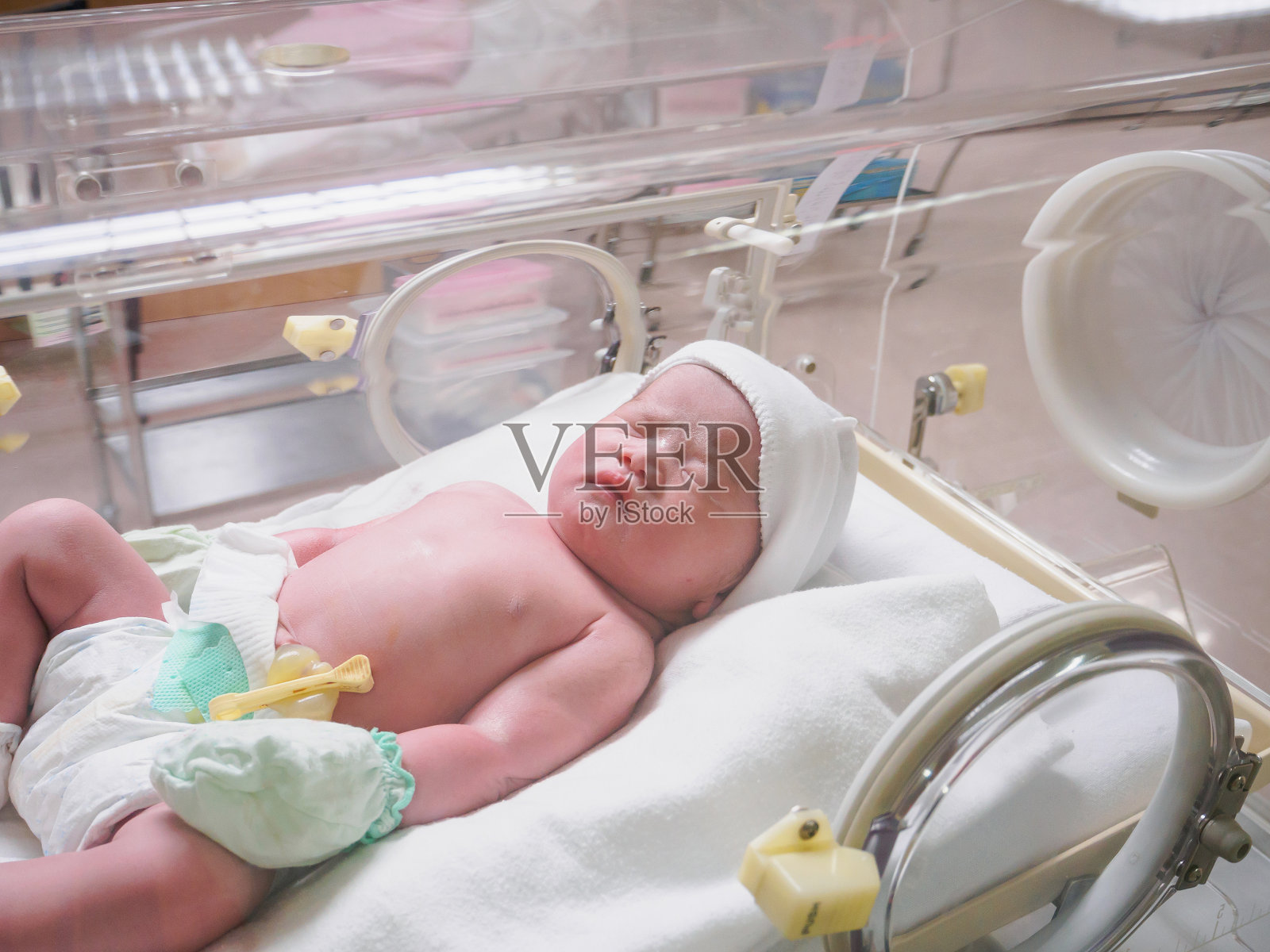 刚出生的婴儿在医院的保温箱里睡觉照片摄影图片