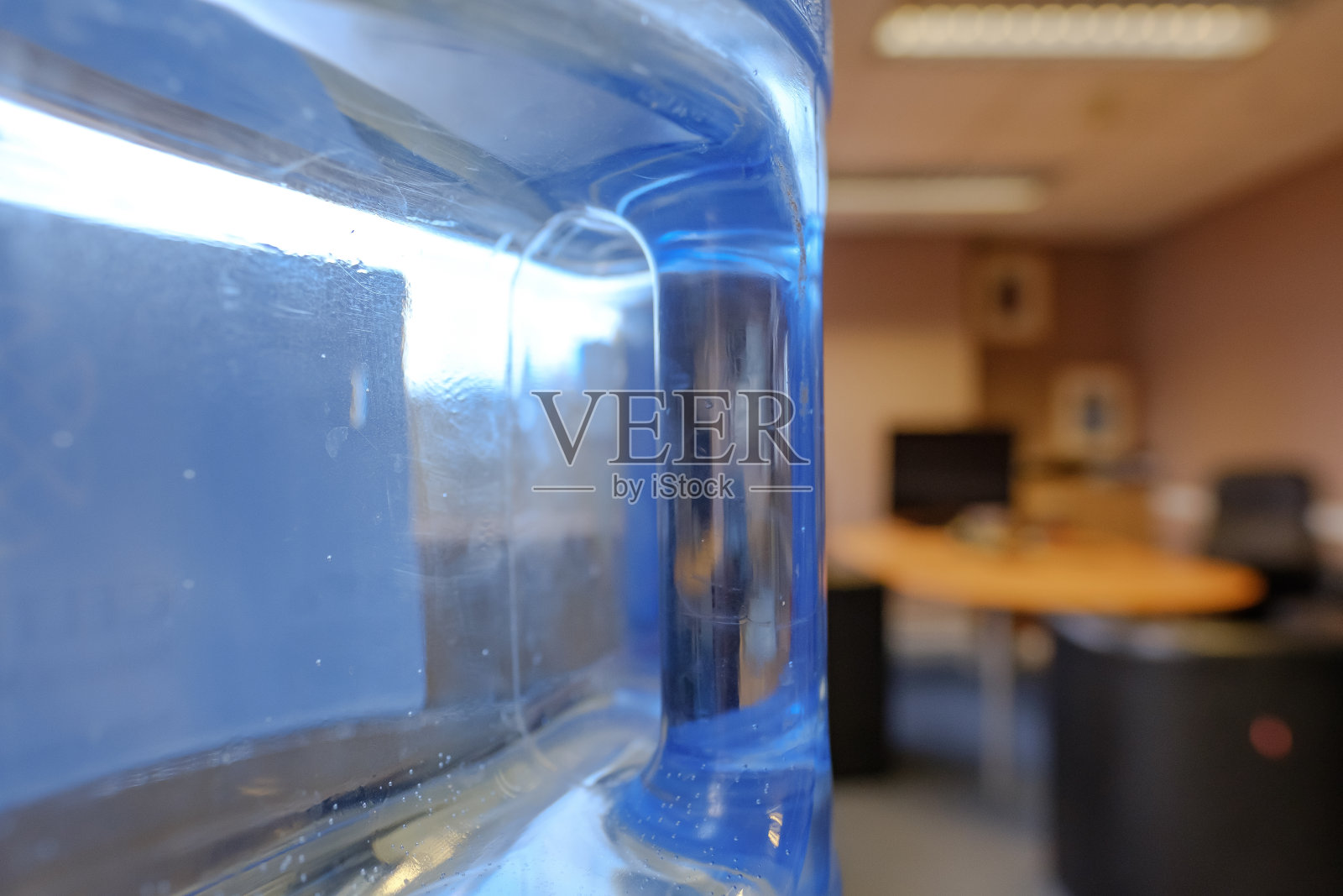 特写，浅焦点的开放式办公室，显示细节的大饮水机瓶和塑料处理与瓶子装满水。照片摄影图片