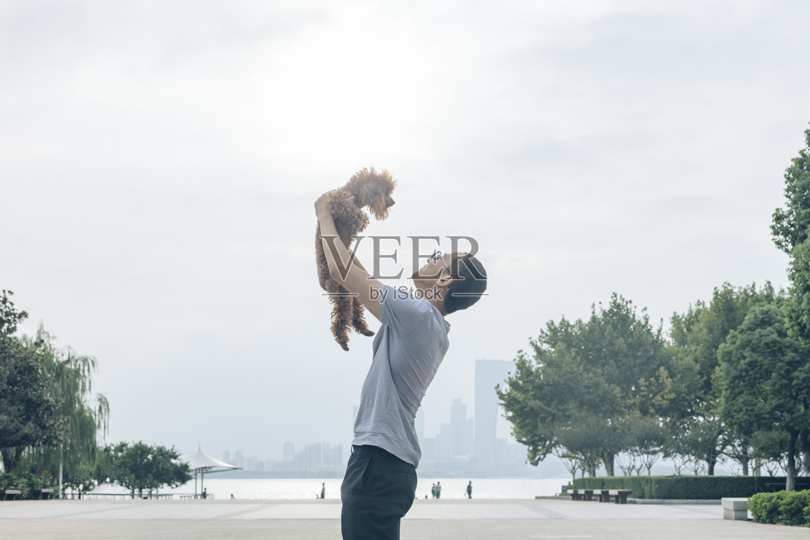 一名男子和他的小狗在城市海滨玩耍照片摄影图片