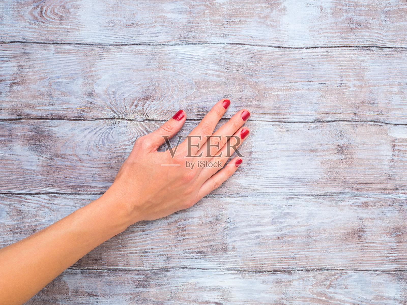 木头表面上涂着红色指甲油的女人的手照片摄影图片