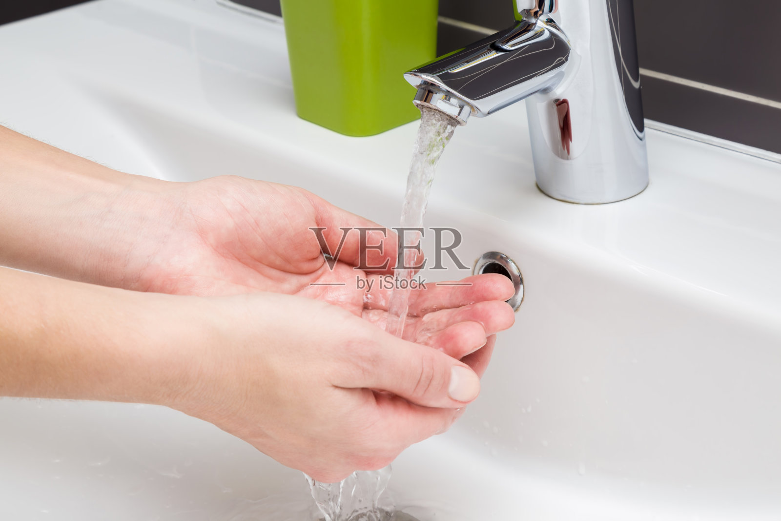 卫生。一个女人在水龙头下的陶瓷水槽里洗手。水运行。健康的生活方式的概念。照片摄影图片