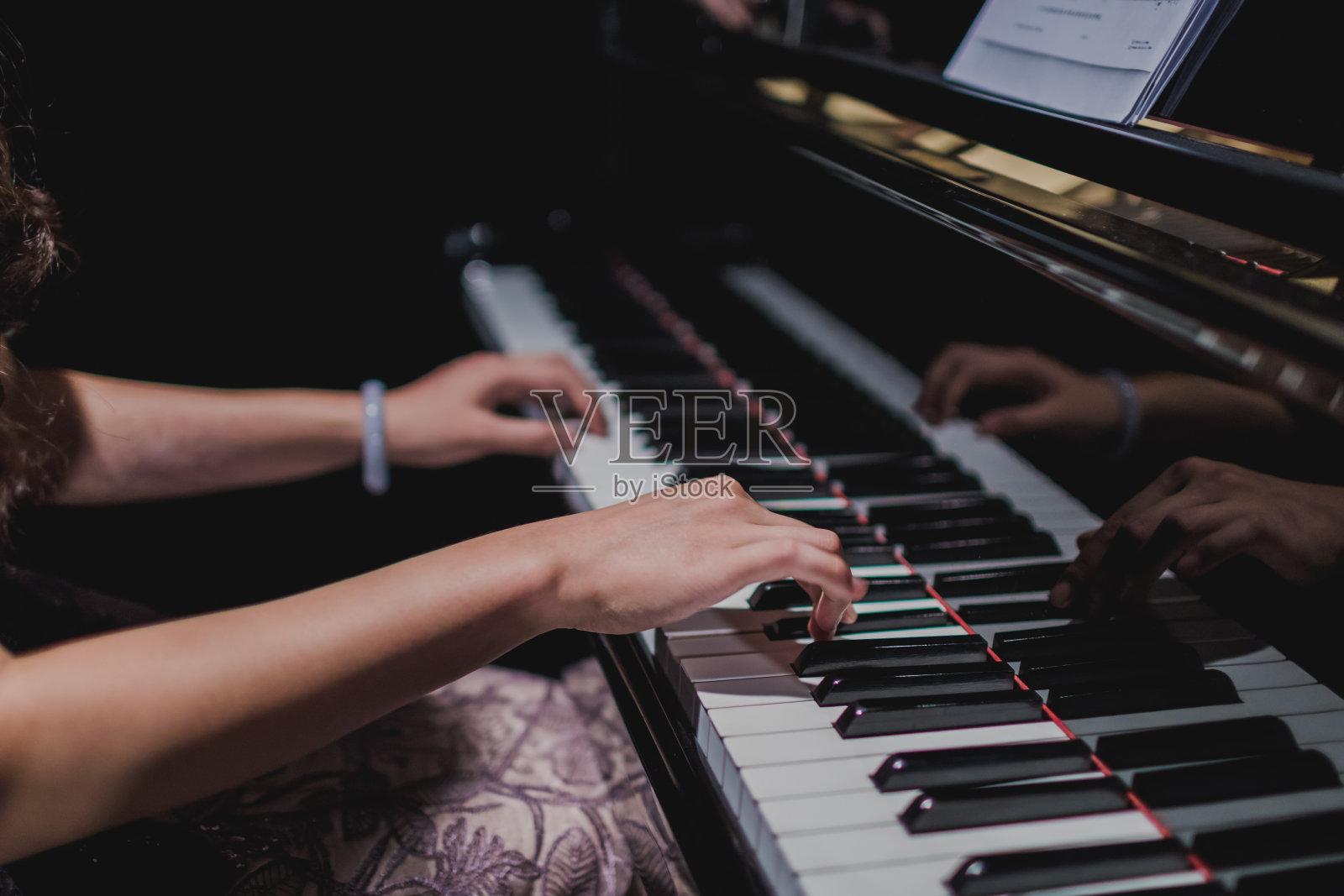 女钢琴家的手在钢琴键盘上。照片摄影图片