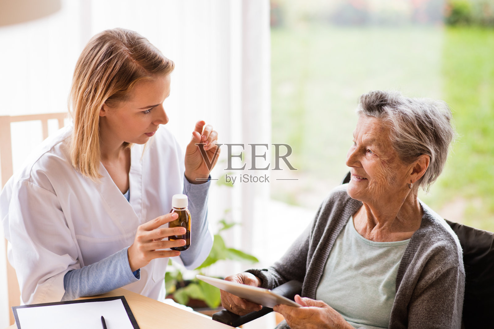 健康访视员和一位服用药片的老年妇女。照片摄影图片