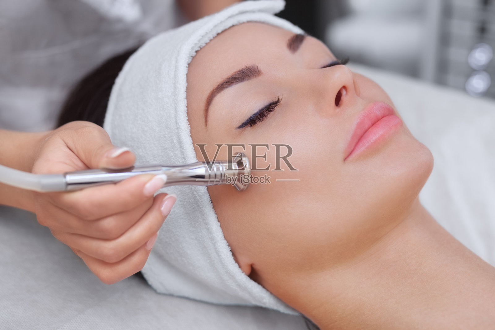 美容师用微晶换肤术给一位美丽年轻的女士做面部皮肤照片摄影图片