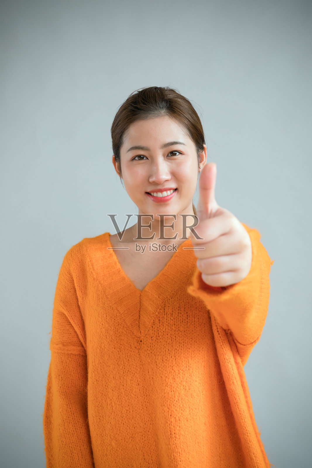 兴奋的亚洲女孩竖起大拇指，在工作室拍照照片摄影图片