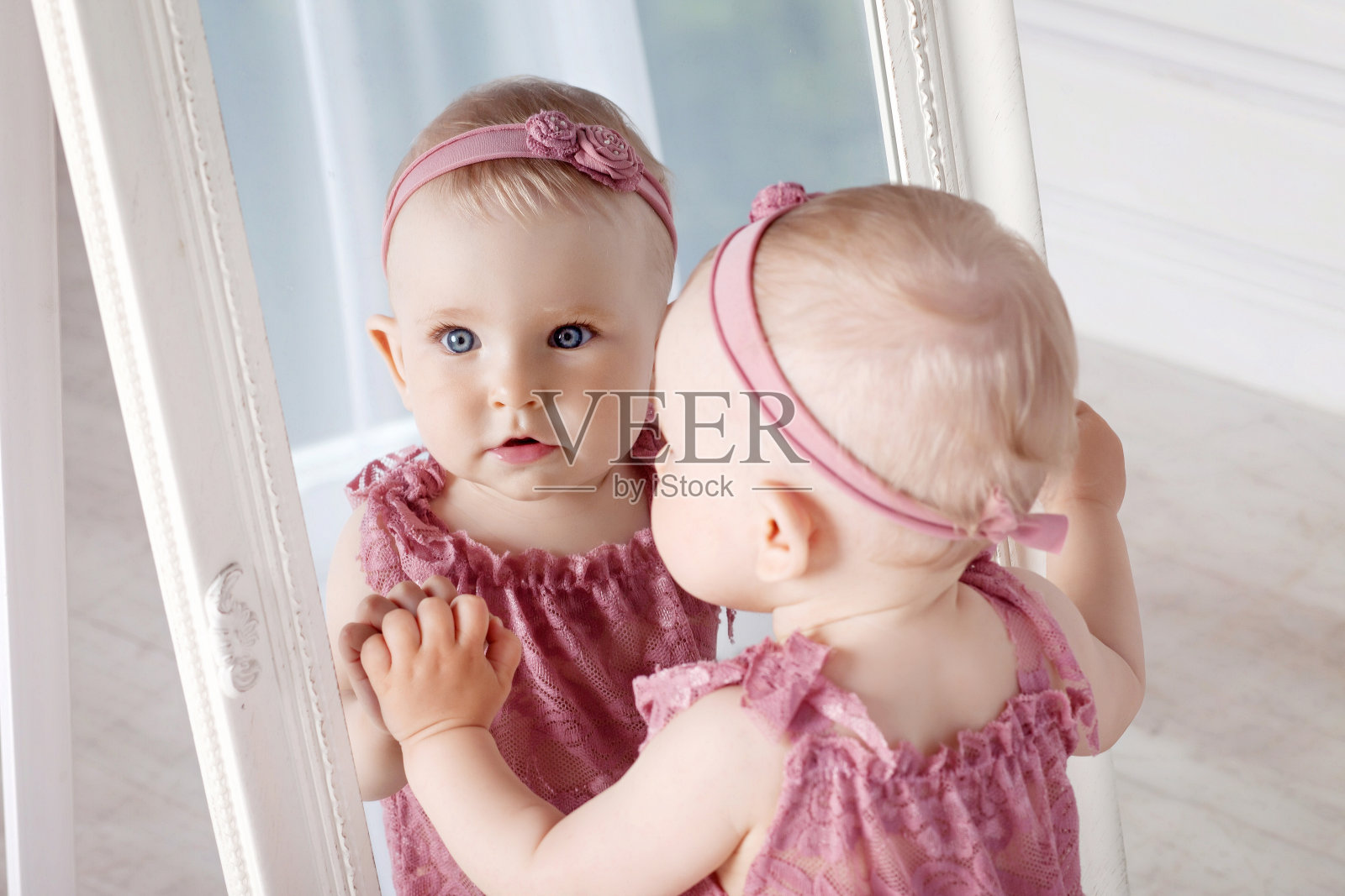 漂亮的小女孩在玩一面大镜子。镜子里的小女孩的肖像照片摄影图片