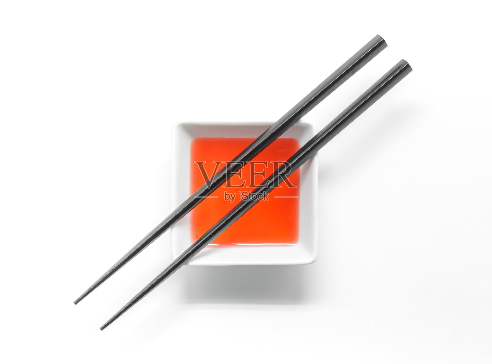 木筷子上的糖醋汁碗孤立在白色的背景。照片摄影图片