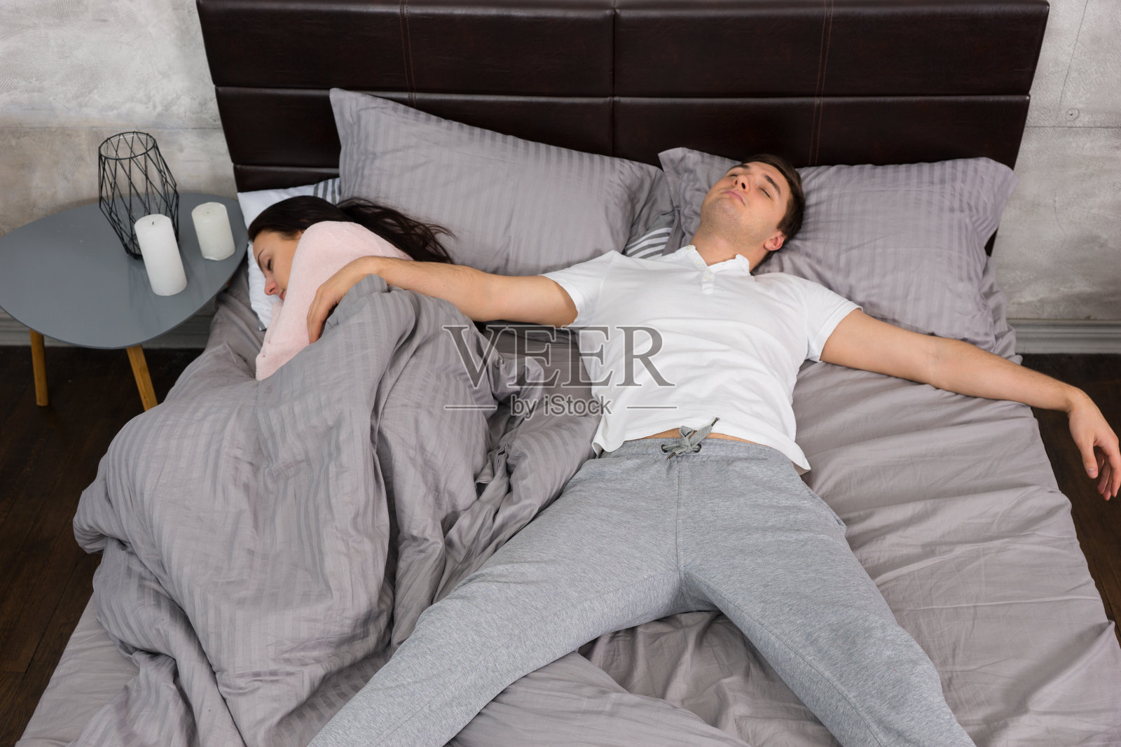 一名年轻男子穿着睡衣和女友以自由落体睡姿占据了整张床照片摄影图片