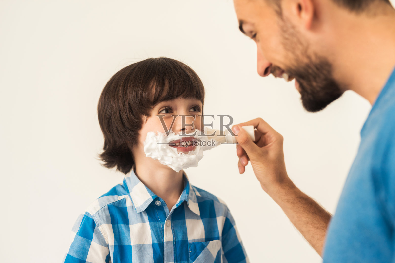 父亲在浴室里教儿子刮胡子。照片摄影图片