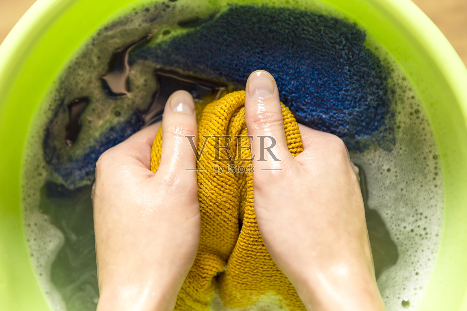 女性用手在盆里洗颜色的衣服照片摄影图片