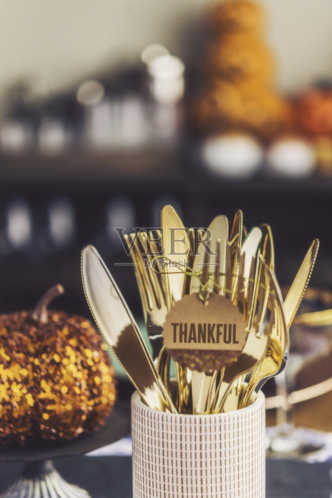 感恩节餐桌上有豪华的金色餐具和闪闪发光的南瓜照片摄影图片