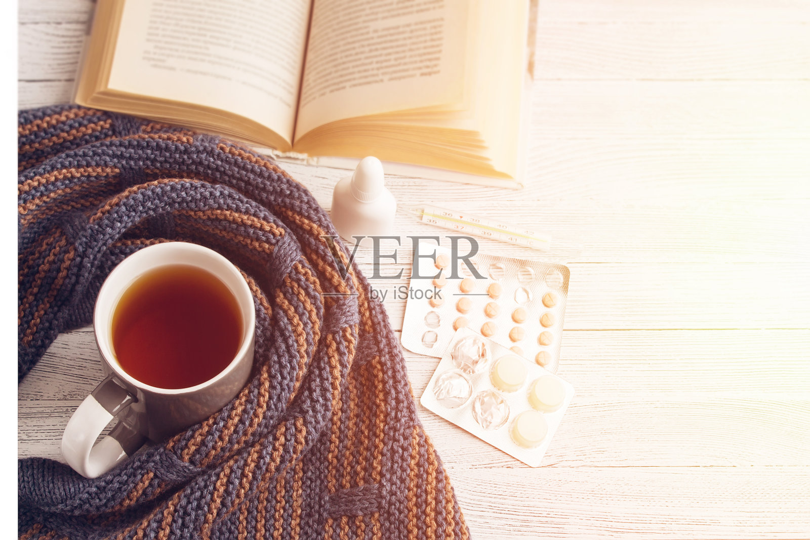 一杯茶，一本书，体温计，药片，编织围巾在一个轻的背景。照片摄影图片